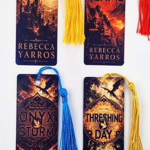 May include: Four rectangular bookmarks featuring fantasy illustrations of castles, dragons, and text. The bookmarks are titled Fourth Wing, Iron Flame, Onyx Storm, and Threshing Day by Rebecca Yarros, each with a colorful silk tassel attached at the top.