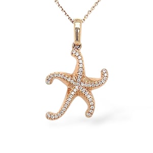 May include: A rose gold starfish pendant necklace. The starfish is encrusted with small, sparkling clear stones. The necklace chain is delicate and also rose gold. The pendant hangs from a small loop at the top of the starfish.