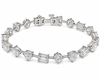 May include: A silver-toned metal bracelet featuring a repeating pattern of clear, faceted stones in various shapes, including round, emerald-cut, and pear-cut, connected by thin metal links and secured with a rectangular box clasp closure.
