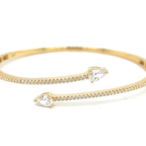 May include: A gold-toned cuff bracelet with a delicate design. The bracelet features a row of small, sparkling stones along the band and two pear-shaped, clear gemstones at the ends. The bracelet is set against a white background.