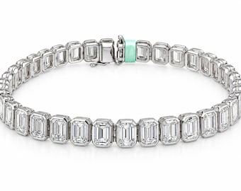 May include: A silver-toned tennis bracelet featuring a continuous row of rectangular emerald-cut clear stones set in individual metal frames. The bracelet includes a secure metal clasp mechanism with a distinct light mint green accent piece.
