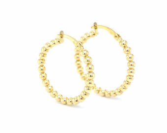 May include: A pair of gold-colored hoop earrings. Each earring is adorned with small, evenly spaced beads around the entire hoop. The earrings are displayed against a white background.