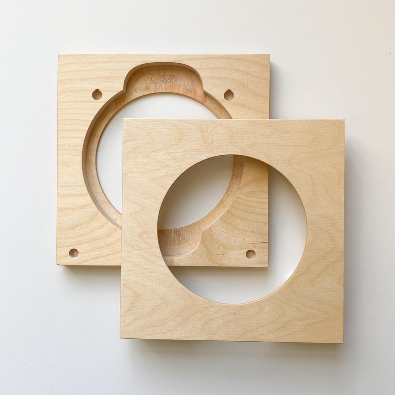 Puede incluir: Dos bafles de altavoz de madera sin terminar con recortes circulares. Los bafles son cuadrados y tienen un color de madera claro.