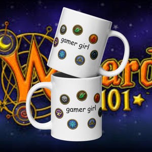 May include: Two white ceramic mugs stacked on top of each other. Each mug has the text "gamer girl" and various colorful circular icons. The background is a dark blue with orange and gold text.