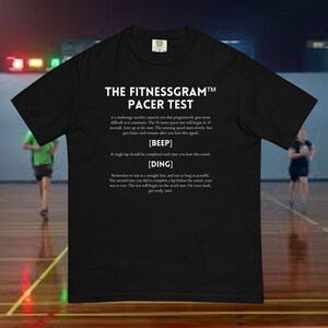 Könnte beinhalten: Schwarzes T-Shirt mit weißem Text, der "THE FITNESSGRAM™ PACER TEST" lautet und die Regeln des Tests erklärt. Der Text enthält die Wörter "BEEP" und "DING" in eckigen Klammern.