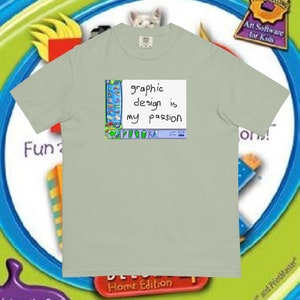 Puede incluir: Una camiseta verde claro con un gráfico de una pantalla de computadora que muestra el texto "graphic design is my passion".