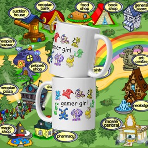 Peut inclure: Deux mugs en c&eacute;ramique blanche superpos&eacute;s. Chaque mug porte l'inscription "gamer girl" avec des cr&eacute;atures de dessins anim&eacute;s color&eacute;es. L'arri&egrave;re-plan est une carte avec des boutiques et des b&acirc;timents.