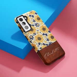 May include: A phone case with a sunflower pattern and a brown wood-like bottom. The bottom has the name "Charlotte" written in white script.