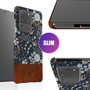 May include: A slim phone case with a floral pattern in shades of blue, green, and white. The case has a brown leather-like bottom and a clear back to show the phone.