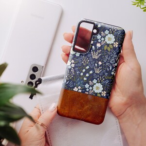 May include: A blue and brown phone case with a floral pattern. The case has a clear cutout for the camera lens.