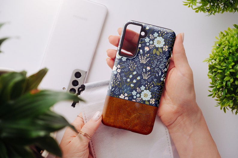 May include: A blue and brown phone case with a floral pattern. The case has a clear cutout for the camera lens.