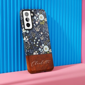 May include: A blue and white floral phone case with a brown wood-grain bottom and the name "Charlotte" engraved in white.