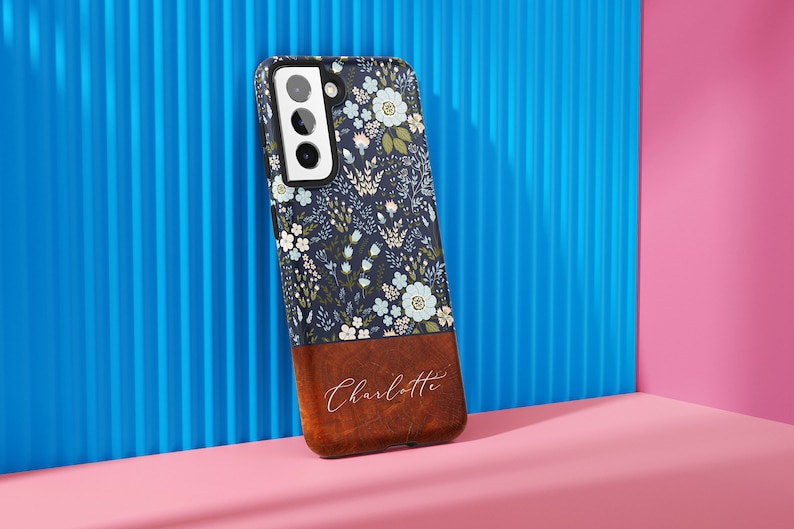 May include: A blue and white floral phone case with a brown wood-grain bottom and the name "Charlotte" engraved in white.