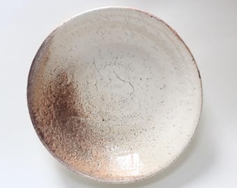 May include: A white ceramic bowl with a brown glaze on the bottom half. The bowl has a crackled glaze and a slightly uneven rim.