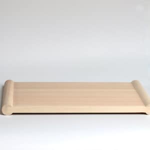 May include: A light-colored wooden serving tray with rounded ends. The rectangular tray is made of light-colored wood and has a smooth, natural finish. The ends of the tray are curved, adding a decorative element to the design.