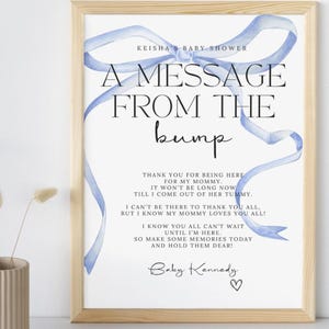 Può includere: Un nastro blu con un messaggio dalla pancia per una baby shower. Il messaggio dice: "Grazie per essere qui per la mia mamma. Non passerà molto tempo prima che esca dalla sua pancia. Non posso essere lì per ringraziarvi tutti, ma so che mia mamma vi ama tutti! So che voi tutti non vedete l'ora che io sia qui. Quindi create dei bei ricordi oggi e conservateli con cura. Baby Kennedy"