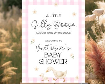 May include: A baby shower sign on an easel with a pink gingham border. The sign reads "A Little Silly Goose is About to be on the Loose! Welcome to Victoria's Baby Shower" with a graphic of a goose and gosling.
