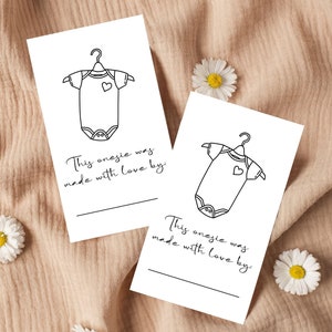 May include: Two blank white cards with a black outline of a onesie and the text "This onesie was made with love by:" on each card.