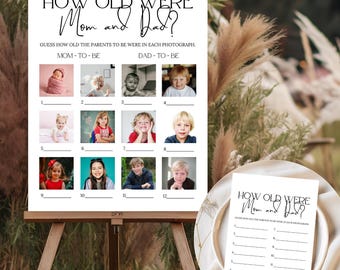 May include: A white sign on a wooden easel with the text "HOW OLD WERE Mom and Dad?" and a game to guess the parents' ages in photos. The sign includes 12 numbered photo slots and a smaller version on a plate.