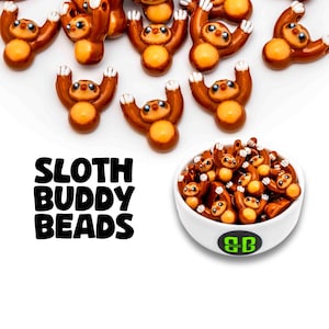 May include: A collection of brown and tan sloth-shaped beads with white claws, scattered around a small white bowl filled with more beads. The text SLOTH BUDDY BEADS is printed in black, and the bowl features a circular logo with the letters SB.