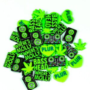 May include: A collection of green and black resin charms with various phrases and designs, including "Where's Molly", "Bass Head", and "PLUR".