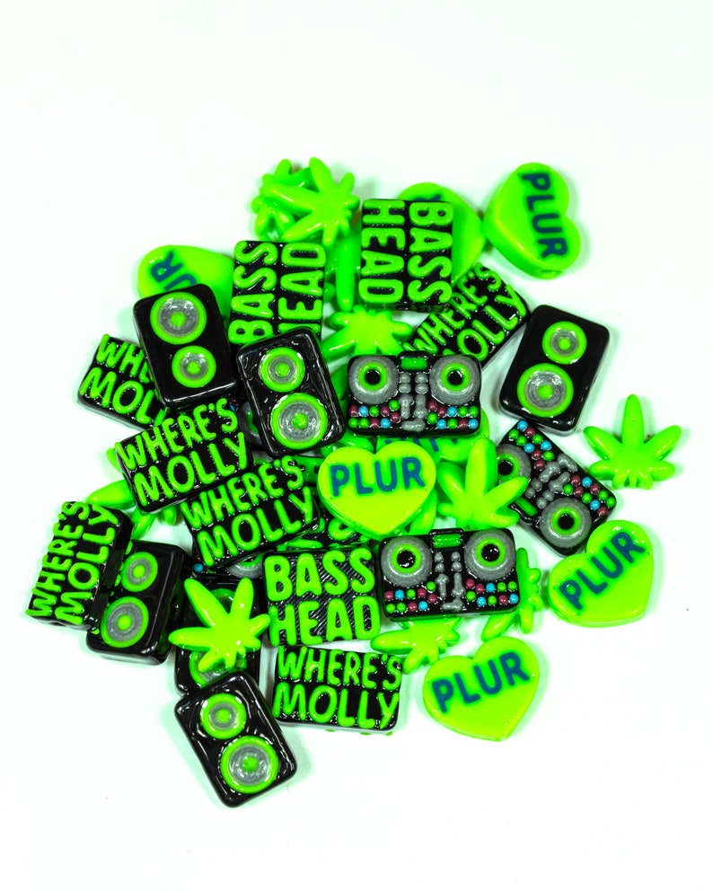 May include: A collection of green and black resin charms with various phrases and designs, including "Where's Molly", "Bass Head", and "PLUR".