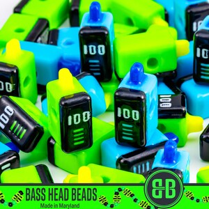 May include: A collection of colorful, plastic beads in shades of blue, green, and yellow. Each bead has a black screen displaying "100" and a battery indicator. The beads are labeled "BASS HEAD BEADS" and "Made in Maryland".