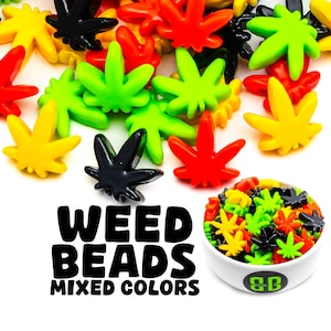 May include: A bowl of colourful weed leaf shaped beads in black, green, yellow, and red. The bowl is white with a black and green logo that says "GB". The text "WEED BEADS MIXED COLORS" is in black letters on a white background.
