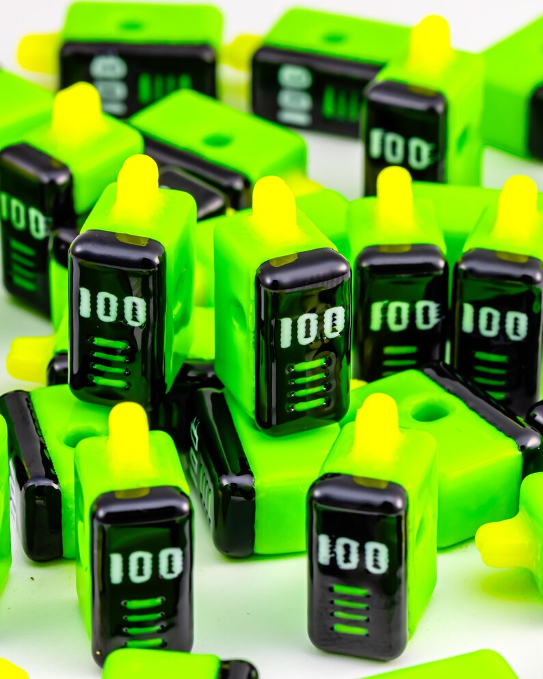 May include: Bright green and black rectangular objects with a yellow top and the number "100" in white. The objects are scattered across a white surface. The objects have a digital display.