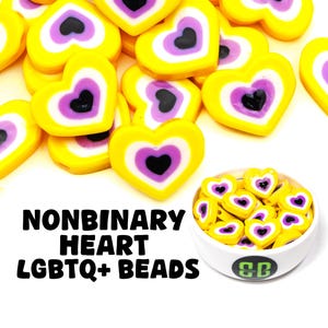 May include: A bowl of yellow, white, and purple heart-shaped beads with a black heart in the center. The beads are labeled "Nonbinary Heart LGBTQ+ Beads".