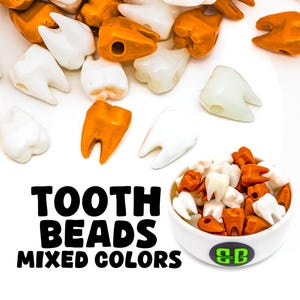 Peut inclure: Des perles en forme de dents de différentes couleurs, blanches et orange. Les perles sont dispersées sur une surface blanche, certaines dans un petit bol blanc. Le texte sur l'image indique "TOOTH BEADS MIXED COLORS."