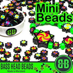 May include: A bowl filled with colorful mini beads with a black and green swirl design. The beads are arranged in a circle around a white bowl with a black and green logo that says "BB". The text "Mini Beads" is written in large green letters above the bowl. The text "Bass Head Beads Made in Maryland" is written in black letters on a green background below the bowl.