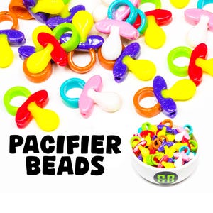 May include: A collection of colorful plastic pacifier beads in various colors, including yellow, red, orange, purple, pink, and blue. The beads are shaped like pacifiers with a ring on the top. The text "PACIFIER BEADS" is written in black letters on a white background.