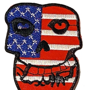 Puede incluir: Un parche bordado de un cráneo con una sonrisa de dientes, en rojo, blanco y azul. El cráneo está dividido en dos, con el lado izquierdo mostrando las estrellas de la bandera estadounidense y el lado derecho mostrando las rayas.