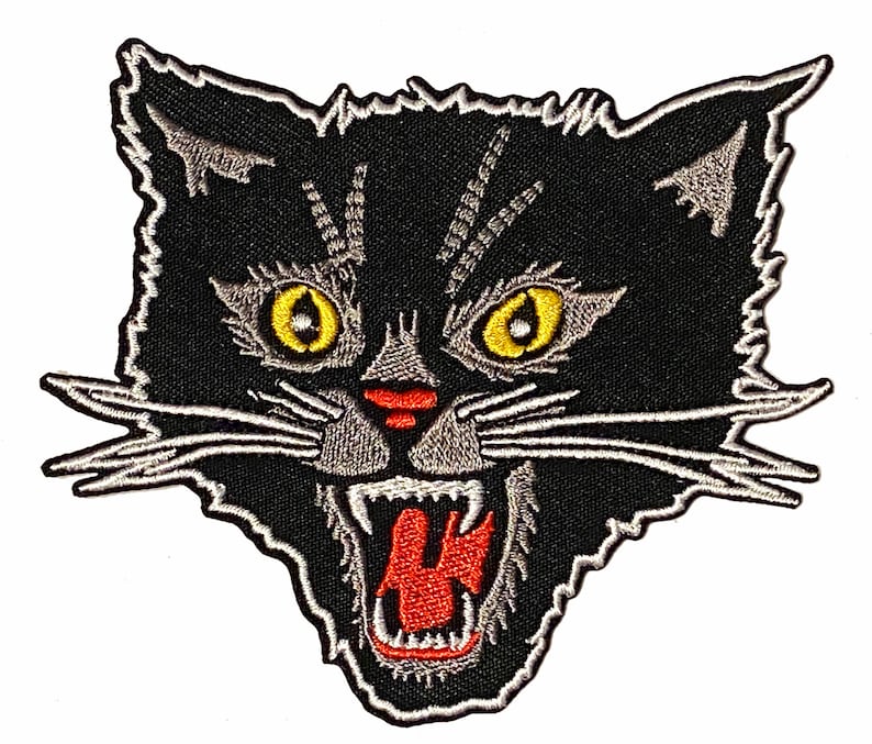 May include: Black and white embroidered patch of a snarling black cat with red mouth and yellow eyes.