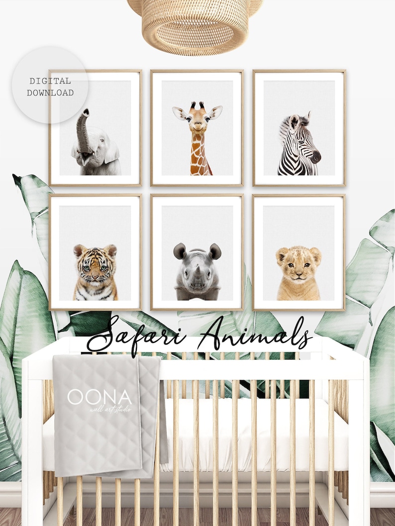 May include: A set of six framed prints featuring close-up images of safari animals, including a giraffe, zebra, elephant, tiger, rhinoceros, and lion. The prints are displayed on a white wall above a white crib with a gray quilted blanket. The text "Safari Animals" is written in black cursive below the prints.