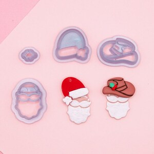 Könnte beinhalten: Ein Set mit sechs Silikon-Ausstechformen in verschiedenen Formen, darunter Weihnachtsmann, Cowboy und Hut. Die Ausstechformen befinden sich auf einem rosa Hintergrund.