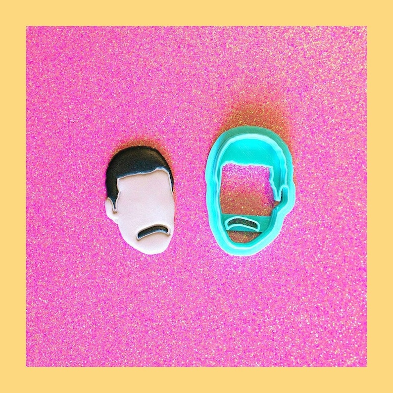 May include: Two cookie cutters, one blue and one white, shaped like a person's face with a mustache.