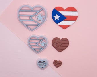 May include: Five heart-shaped cookie cutters, two are blue with a white star and stripes, two are brown with a white star and stripes, and one is red, white, and blue with a white star.