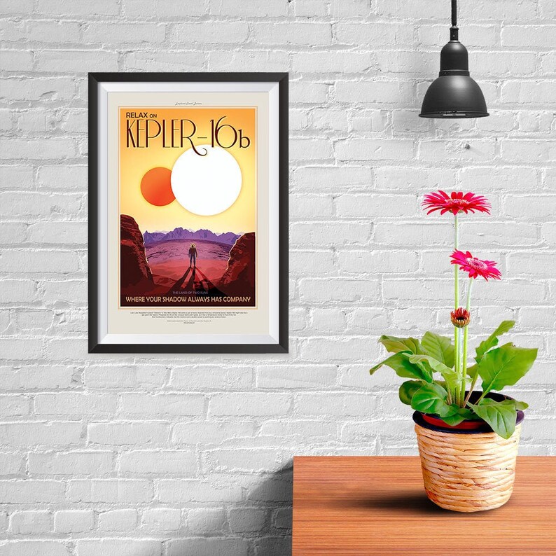 Puede incluir: Un p&oacute;ster enmarcado con un dise&ntilde;o de p&oacute;ster de viaje retro. El p&oacute;ster presenta un sol rojo y naranja y un sol blanco en el cielo sobre un paisaje rocoso. El texto en el p&oacute;ster dice "Relax on Kepler-16b, Where your shadow always has company."