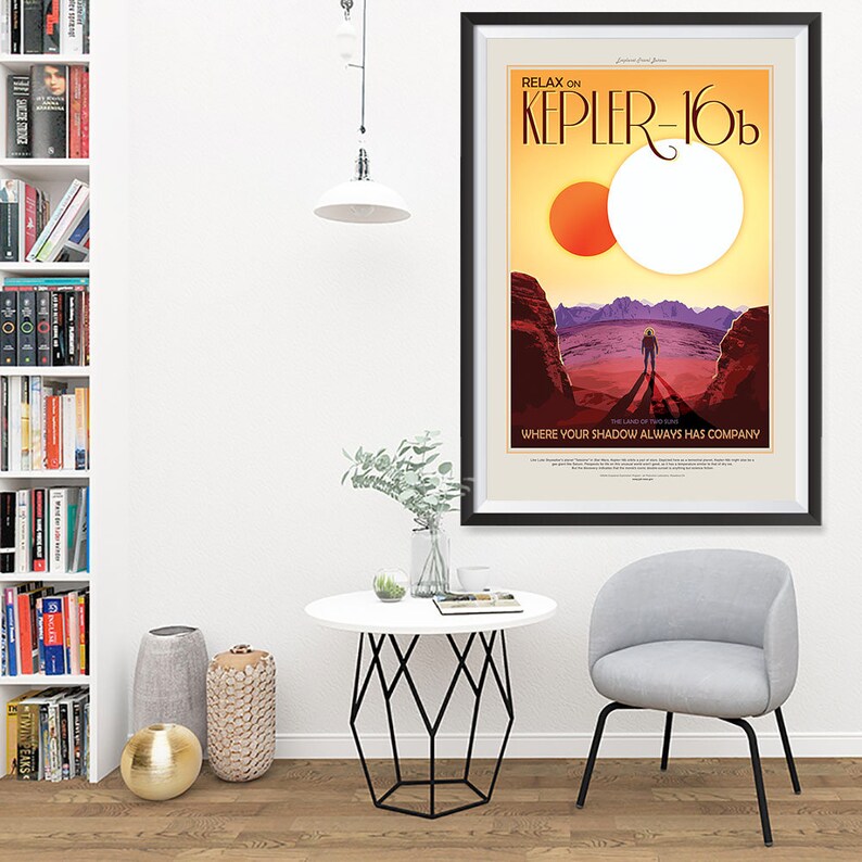 Puede incluir: Un p&oacute;ster enmarcado con un dise&ntilde;o de p&oacute;ster de viaje retro que presenta un sol rojo y blanco, un paisaje rocoso y una figura solitaria con un traje espacial. El texto en el p&oacute;ster dice "Relax on Kepler-16b, The Land of Two Suns, Where your shadow always has company."