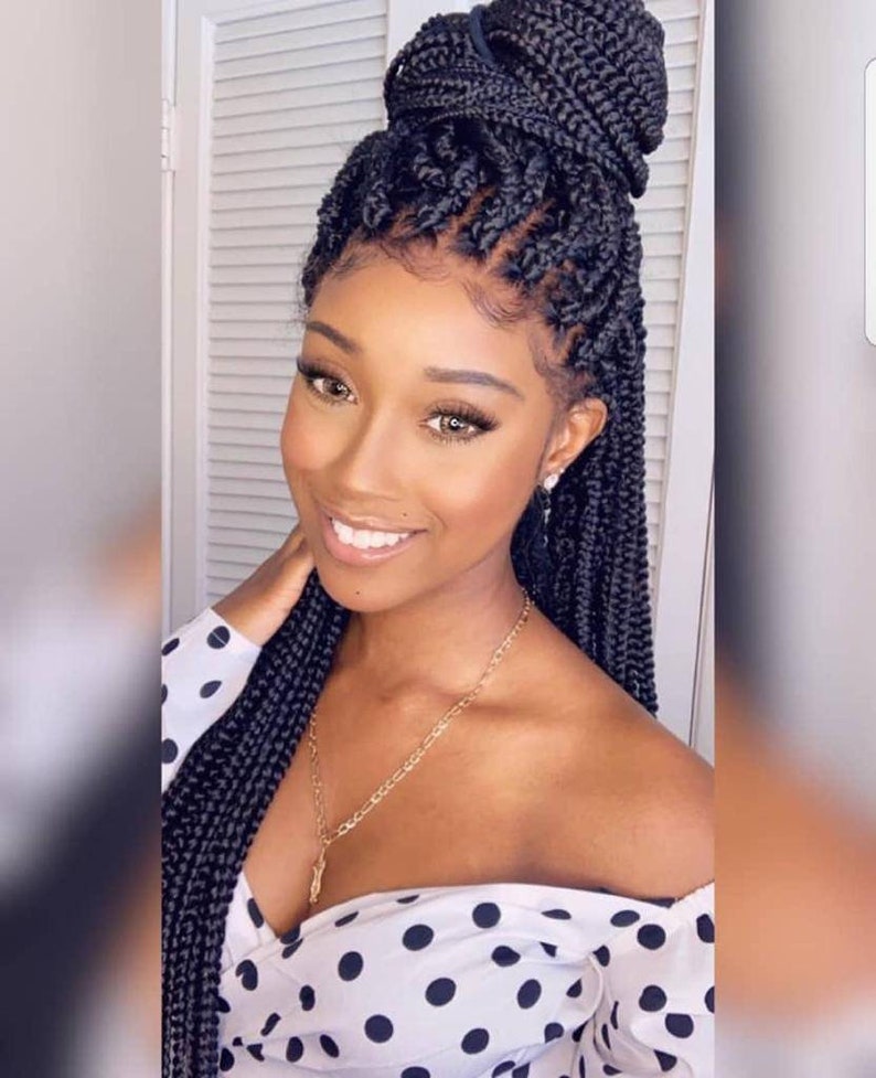May include: A black braided wig with a high ponytail. The wig is styled in a box braid pattern and is worn by a person with dark skin. The person is wearing a white polka dot shirt.