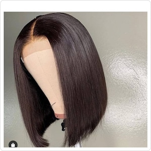 Peut inclure: Une perruque noire de style bob avec une frange en dentelle. La perruque est coiffée en ligne droite et a un aspect naturel et élégant.