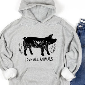 Puede incluir: Una sudadera con capucha gris con una ilustración de cerdo negro y el texto "LOVE ALL ANIMALS".