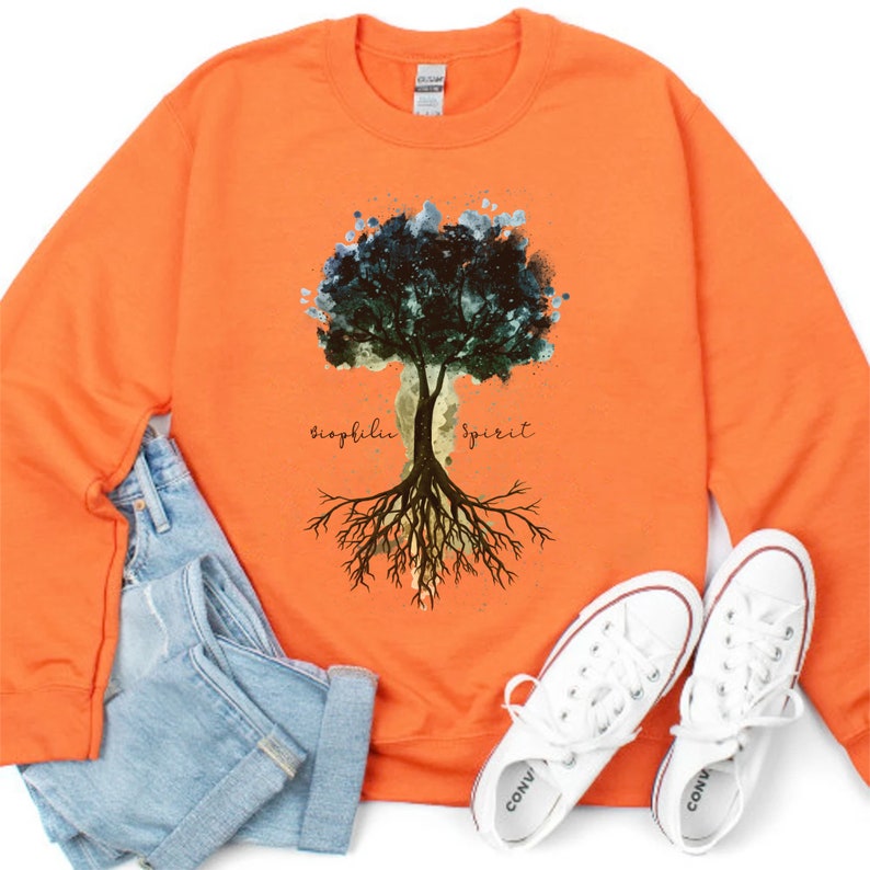 Puede incluir: Sudadera naranja con un dise&ntilde;o de &aacute;rbol de acuarela y las palabras "biophilia spirit" impresas en la parte delantera.