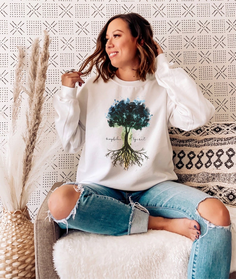 Puede incluir: Sudadera blanca con un dise&ntilde;o de &aacute;rbol de acuarela y las palabras "biophilia" y "spirit" en la parte delantera.