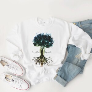 Puede incluir: Sudadera blanca con un dise&ntilde;o de &aacute;rbol de acuarela y las palabras "biophilia" y "spirit" escritas a cada lado del &aacute;rbol.