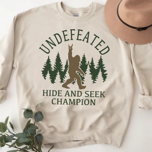 Undefeated Hide and Seek Champion Funny Bigfoot sweatshirt, cryptozoology sweater for Sasquatch Enthusiast, Cryptid mythology shirt