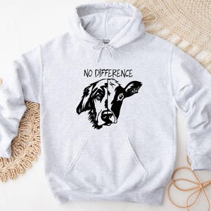 Puede incluir: Una sudadera con capucha gris con el texto "NO DIFFERENCE" impreso en la parte delantera. Debajo del texto hay una ilustración en blanco y negro de una cabeza de perro y vaca combinadas.