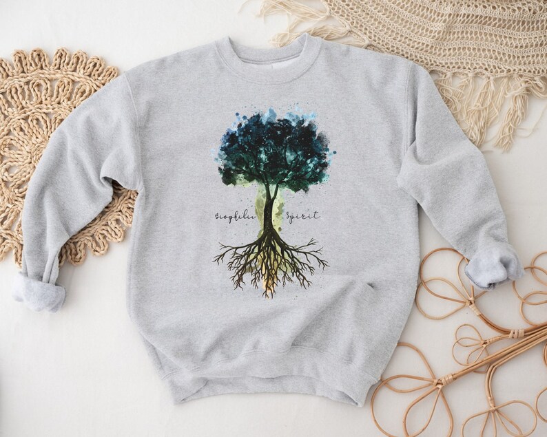 Puede incluir: Sudadera gris con un dise&ntilde;o de &aacute;rbol de acuarela y las palabras "biophilia spirit" impresas en la parte delantera.